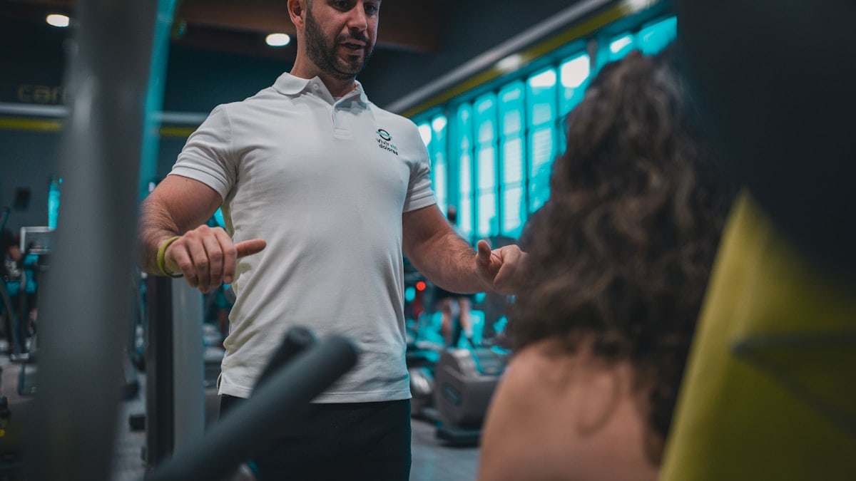 Sesión de entrenamiento en el gimnasio con un entrenador personal, enfocada en el rendimiento y el bienestar físico.
